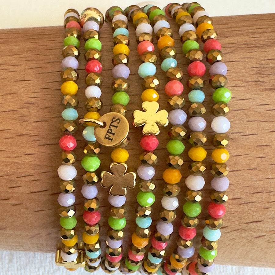 Gros plan sur le trèfle doré intégré au sautoir Candy Pop, bijou en perles de verre multicolores.