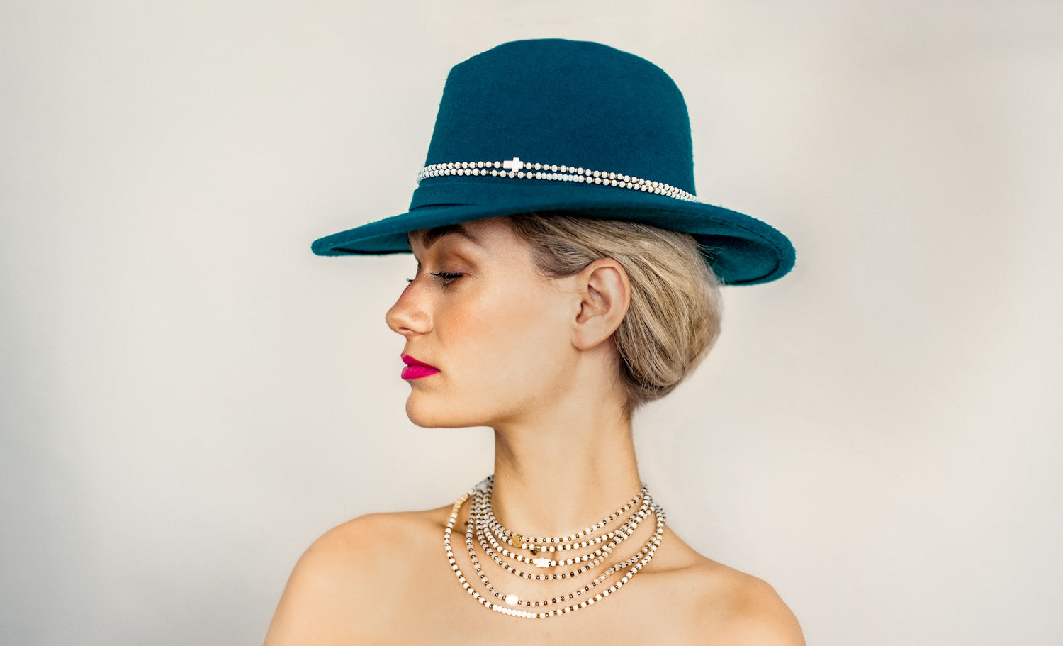 Photo de la collection de colliers de Faispastasteph, portée avec un chapeau élégant. Des bijoux artisanaux qui apportent une touche chic et intemporelle à chaque tenue.