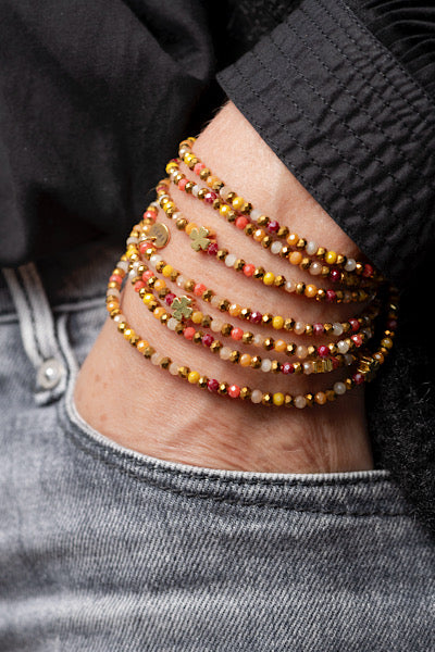 Sautoir Sunset Trèfles Dorés porté en manchette avec perles facettées aux tons chauds et trèfles dorés