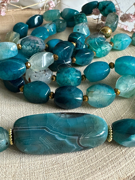 Gros plan sur les perles d’agate torsion du sautoir Céladon, reflets bleus et texture naturelle