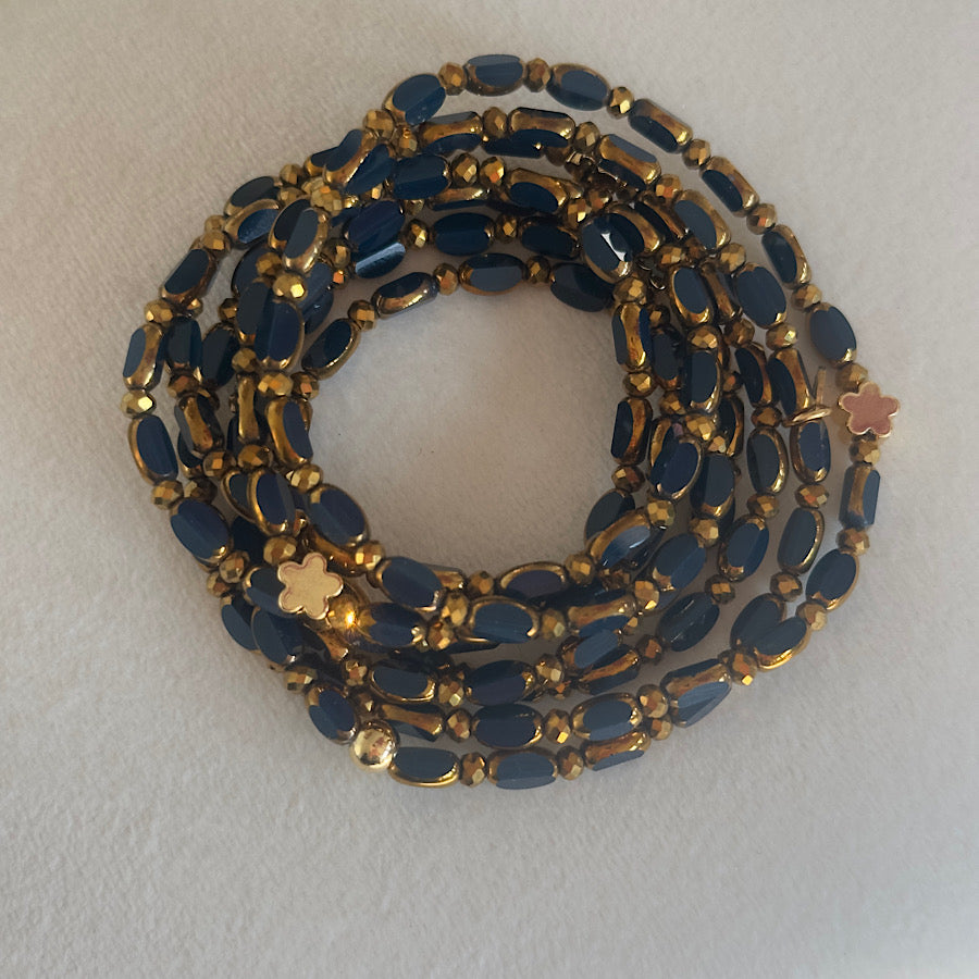 Sautoir Minuit Solaire Fleurs Dorées en perles de verre bleu marine avec fleurs dorées, porté en sautoir long.