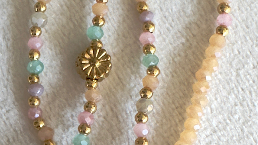 Gros plan sur le sautoir Albella, mettant en avant la finesse des perles de verre de 2 mm et la marguerite dorée en coquillage pastel