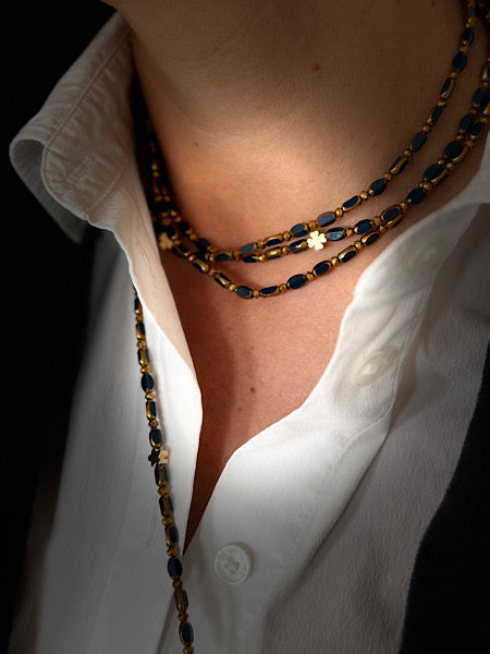 Collier ras de cou Minuit Solaire Trèfles Dorés en accumulation – perles ovales bleues et trèfles dorés lumineux.