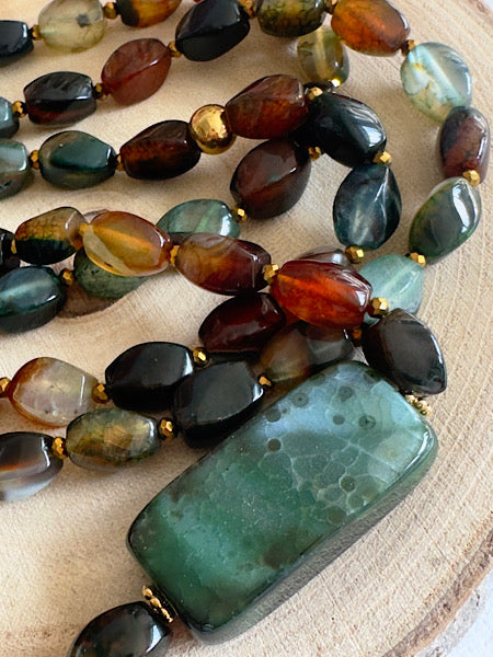 Sautoir Sienna en agates torsion aux nuances vertes ambrées et brunes, pierre centrale verte mise en valeur sur fond clair bijou FAIS PAS TA STEPH