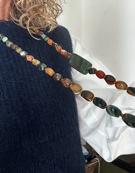 Sautoir Sienna vu de l’autre côté, porté sur pull bleu, perles d’agate torsion aux nuances vert mousse et ambre – bijou unique monté sur fil