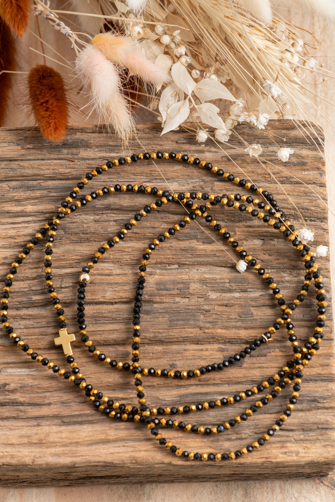 Bijou Vince Croix Dorée, élégant sautoir noir et doré avec perles de verre et croix centrale.