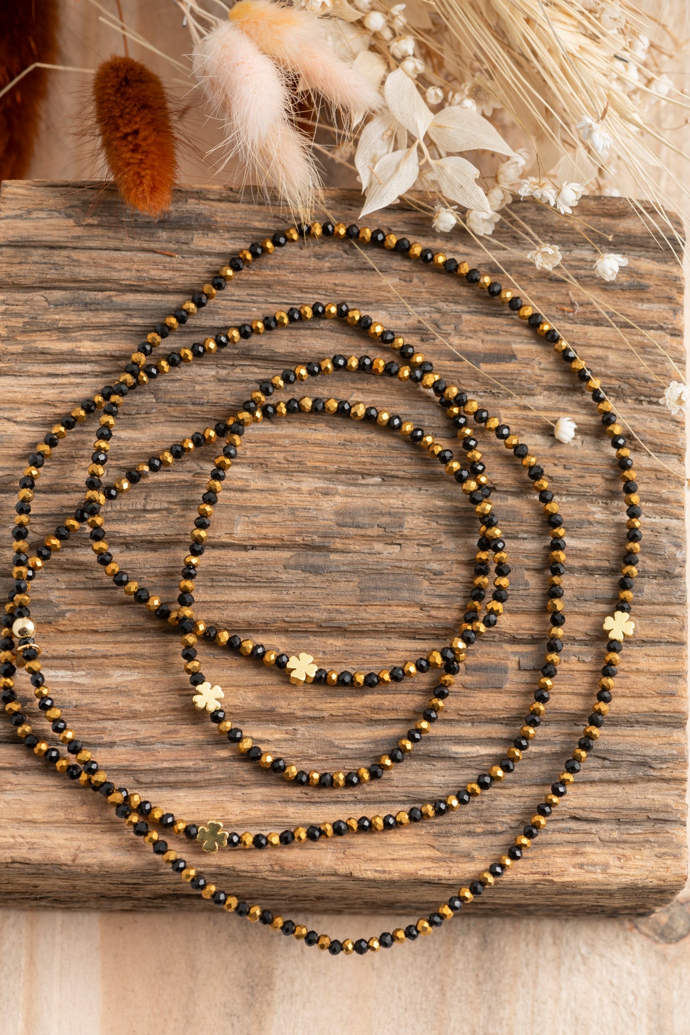 Bijou Vince Trèfles Dorés, élégant sautoir noir et doré aux perles de verre et trèfles dorés intégrés.