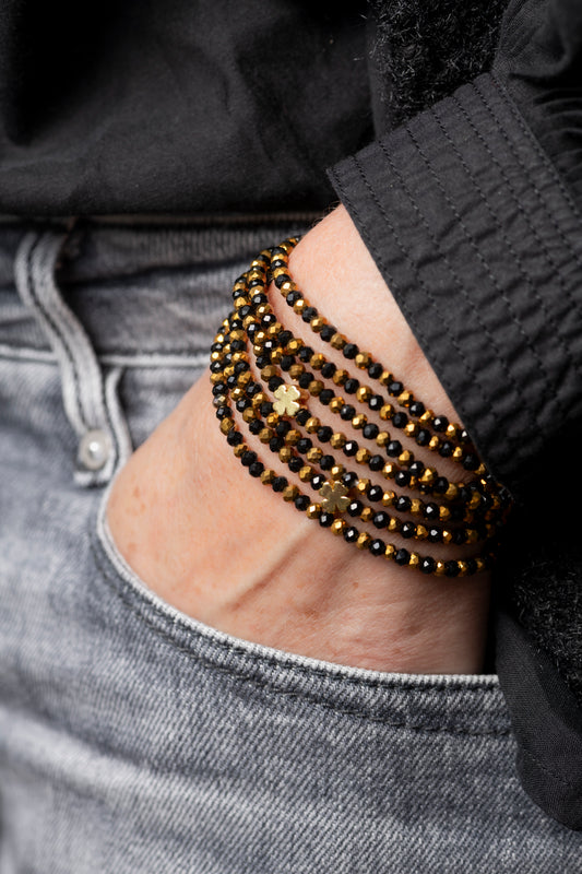 Sautoir Vince Trèfles Dorés en perles de verre noires avec trèfles dorés, porté en sautoir long.