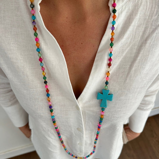 Sautoir Colette multicolore en agate naturelle avec croix turquoise porté sur blouse blanche, perles fines colorées, bijou long fait main
