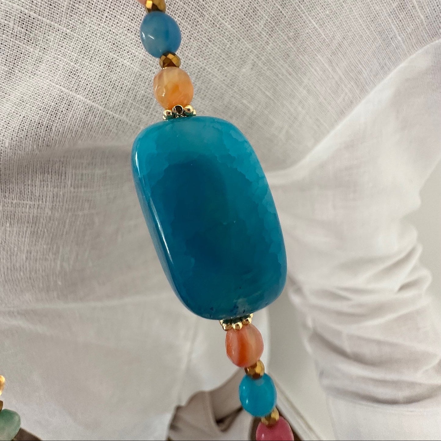 Détail de la pierre bleue rectangulaire du sautoir Colette en agate multicolore, gros plan sur la matière