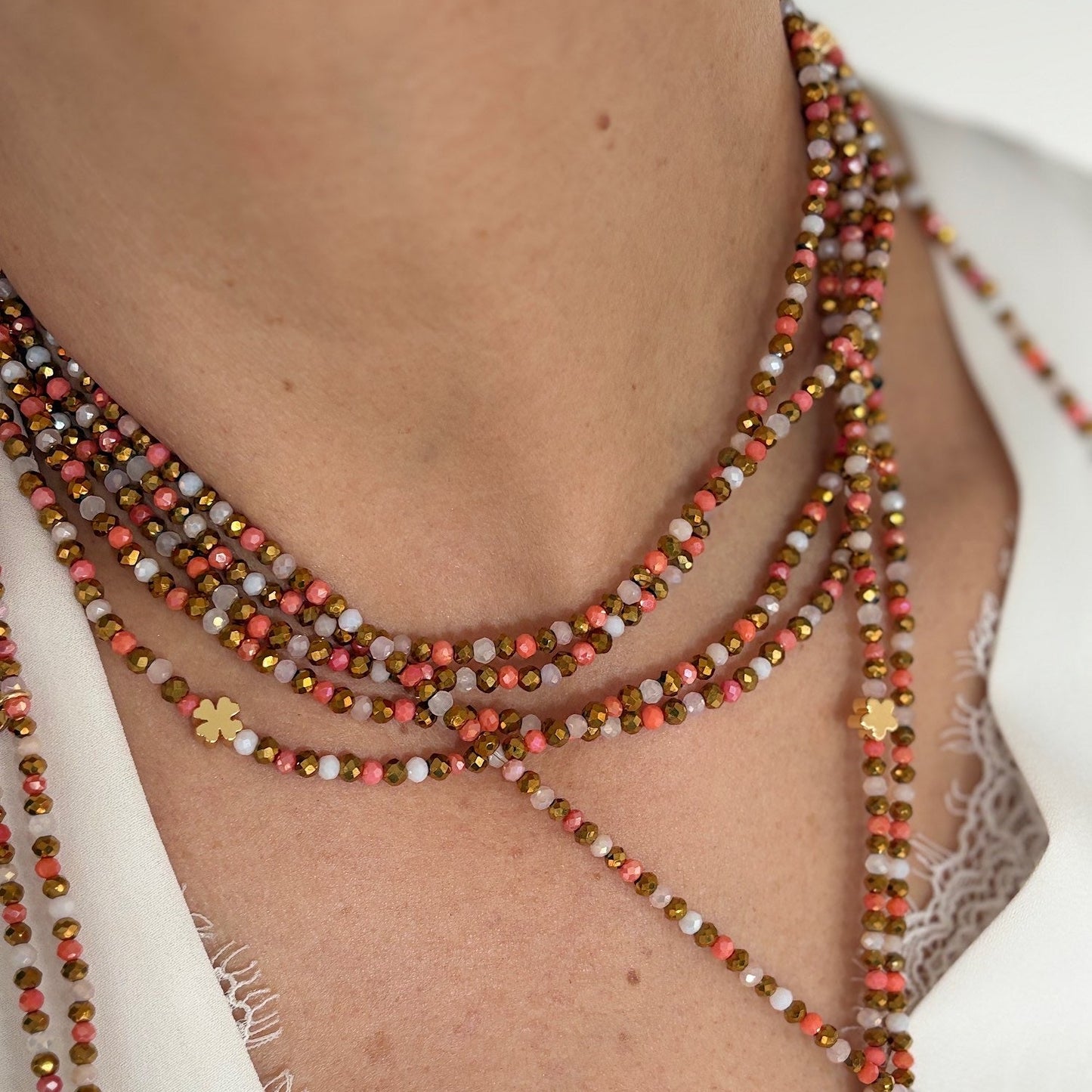 Collier élastique Blush aux trèfles dorés porté en accumulation modulable