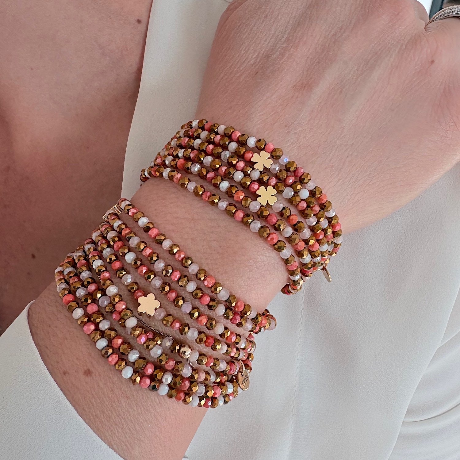 Collier élastique Blush aux trèfles dorés porté en manchette croisée modulable