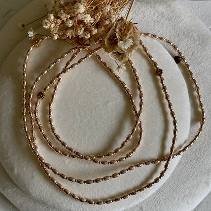 Sautoir doré ultra fin Reflet d’Or porté en collier, perles de verre effet miroir