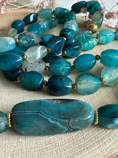 Gros plan sur les perles d’agate torsion du sautoir Céladon, reflets bleus et texture naturelle