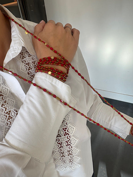 Sautoir Grenat Fleur Dorée porté, perles ovales rouges et fleurs dorées sur chemise blanche