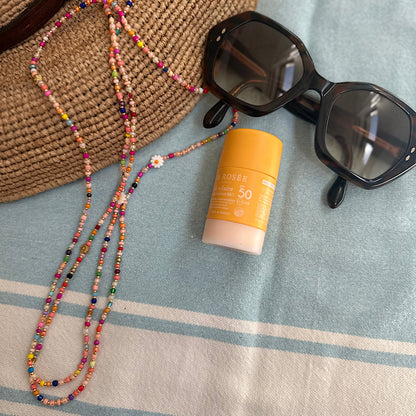Bijou Gribouillis posé sur une fouta avec chapeau de paille, lunettes de soleil et marguerite en coquilla