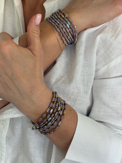 Bracelet 7 tours en perles lila avec trèfles dorés porté au poignet