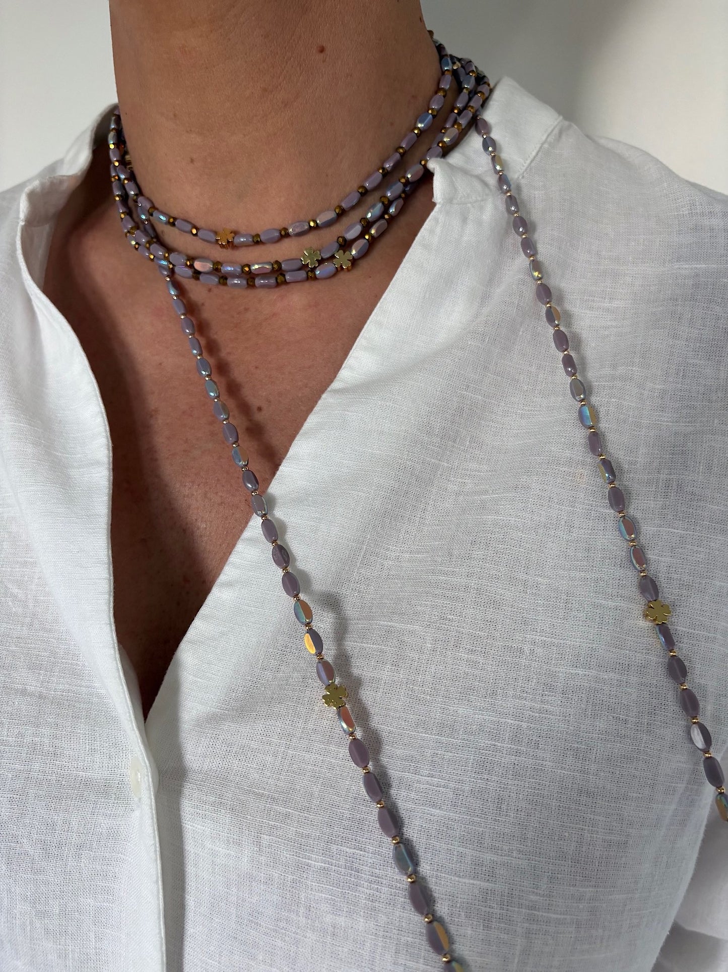 Sautoir en perles lila avec trèfles dorés porté en ras de cou et sautoir