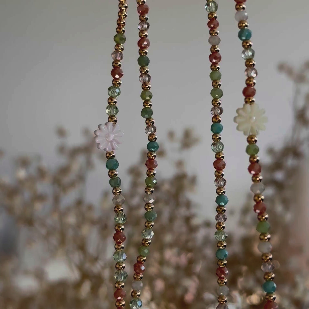 Découvrez le sautoir Fiorella, un bijou délicat en perles de verre ultra-fines (2 mm), aux tons printaniers dominés par le bleu. Orné d’une marguerite dorée en coquillage pastel, ce sautoir raffiné se porte de trois façons : en sautoir (1 tour), en ras de cou (3 tours) ou en manchette (7 tours). Un accessoire polyvalent, léger et élégant, parfait pour illuminer votre style avec subtilité