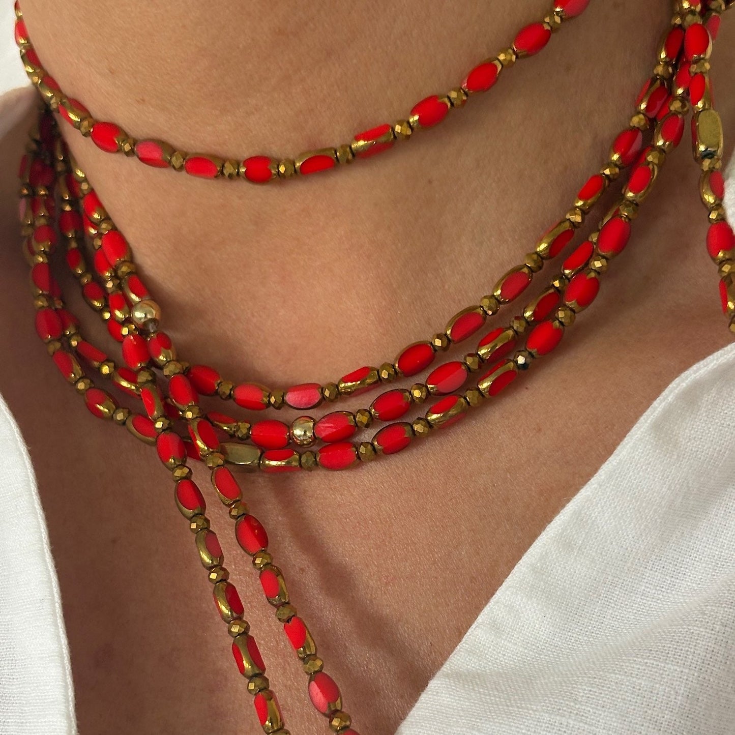 sautoir corail solaire trefles dores en perles de verre rouge orange porte en collier sur chemise blanche