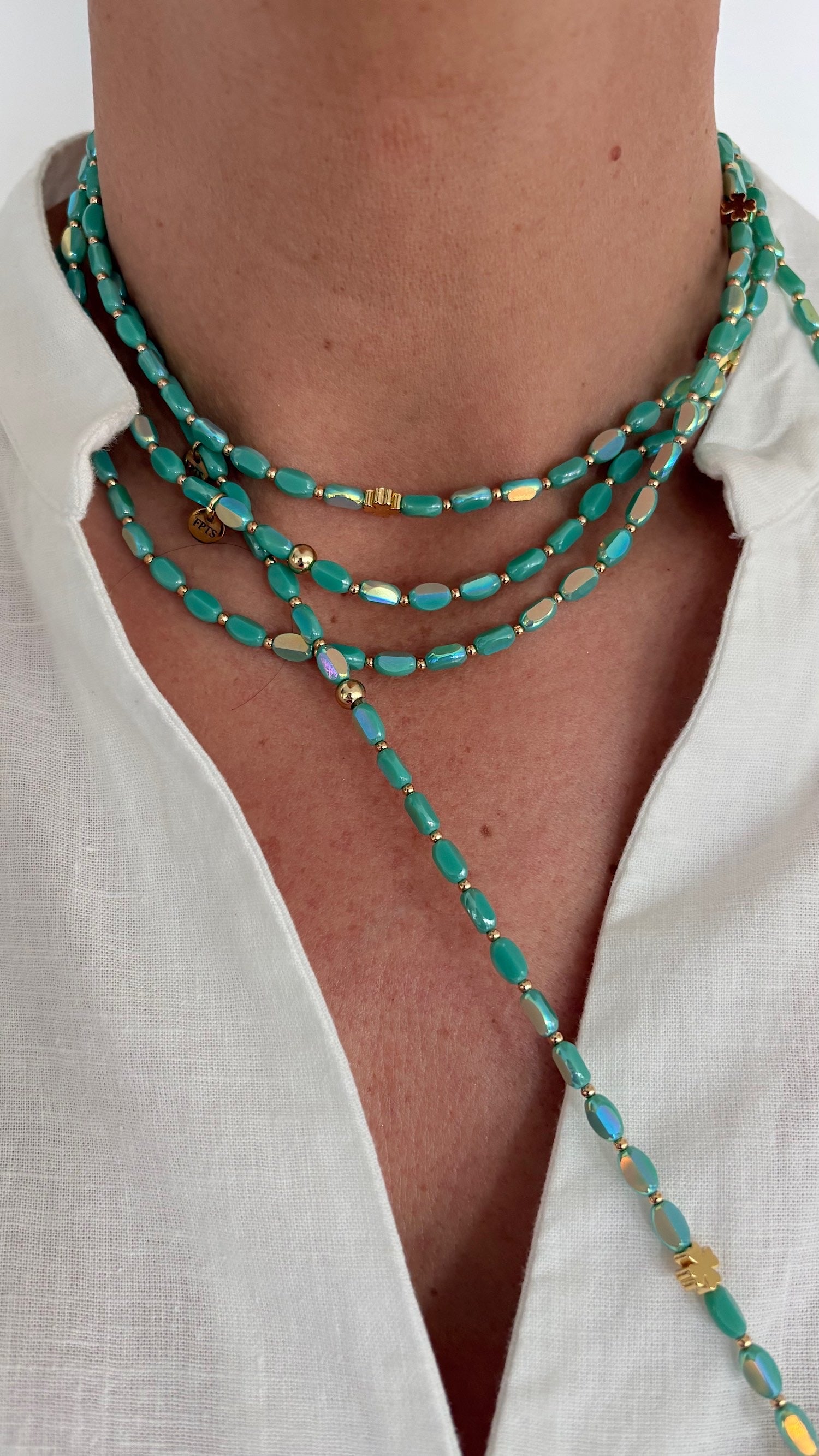 sautoir ovale solaire turquoise en perles de verre et perles ovales dorees porte sur chemise blanche