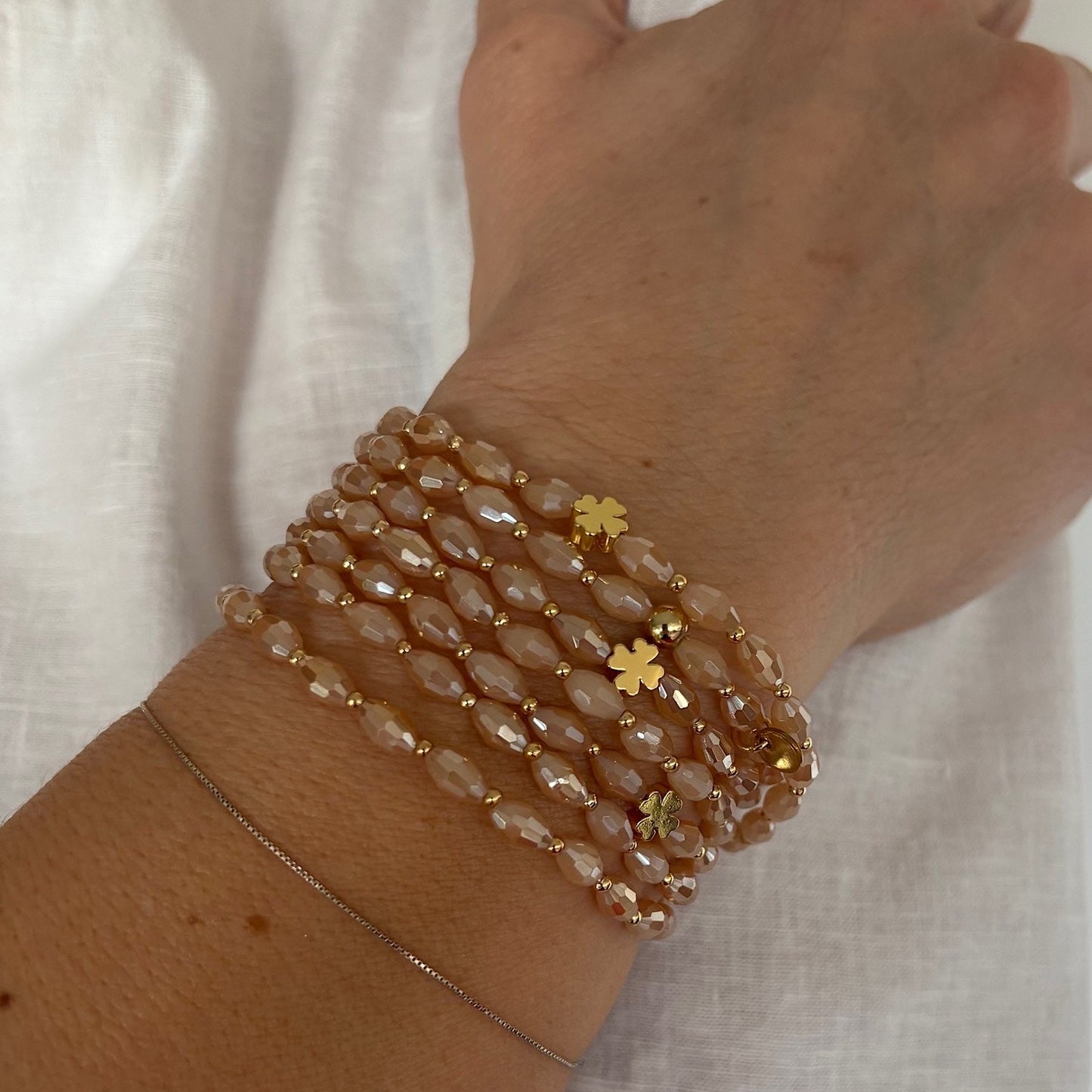 sautoir élastique perles de verre couleur pêche porté en bracelet manchette avec trèfles dorés