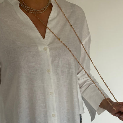 Sautoir en perles de verre pêche solaire porté sur chemise blanche