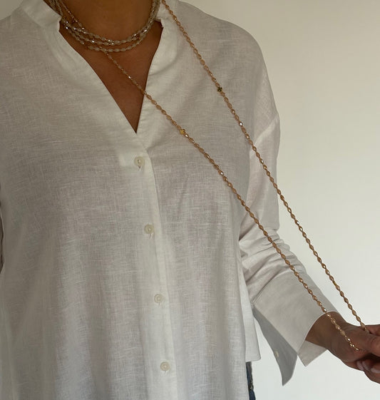 Sautoir en perles de verre pêche solaire porté sur chemise blanche