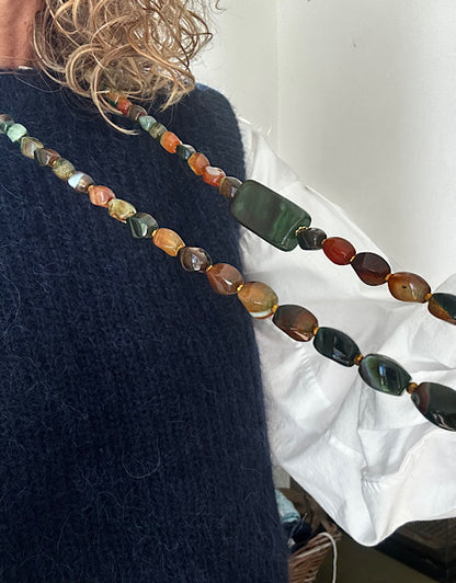 Sautoir Sienna vu de l’autre côté, porté sur pull bleu, perles d’agate torsion aux nuances vert mousse et ambre – bijou unique monté sur fil