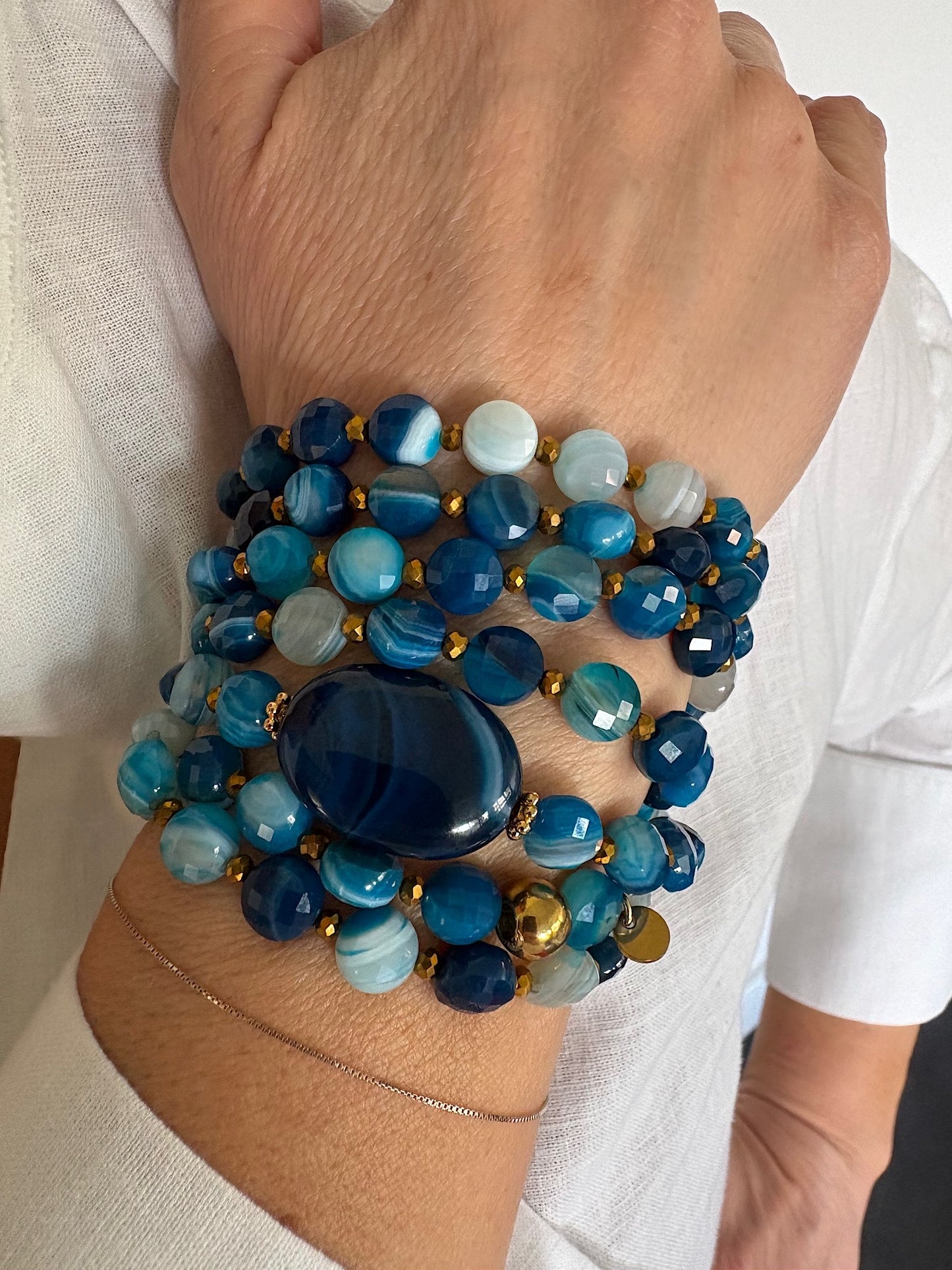 Détail du sautoir Timothée bleu en agate avec perles plates porté en manchette, zoom sur les perles et la pierre centrale