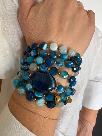Détail du sautoir Timothée bleu en agate avec perles plates porté en manchette, zoom sur les perles et la pierre centrale