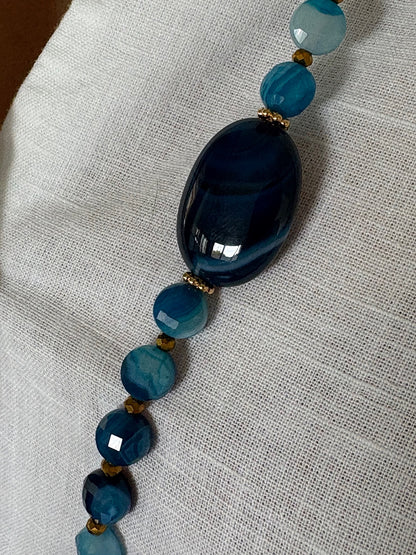 Détail du sautoir Timothée bleu avec pierre centrale en agate et perles plates, zoom sur la matière du bijou